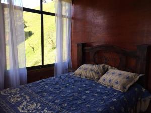 1 dormitorio con 1 cama con edredón azul y ventana en Navarro mountain, en Cartago