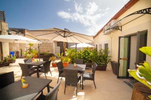 a patio with tables and chairs and an umbrella at B&B Ninfeo Siracusa in Syracuse