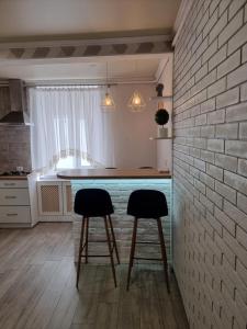 a kitchen with two bar stools and a brick wall at Danyla Galytskogo apartment Центр міста, старе місто 5хв in Kamianets-Podilskyi