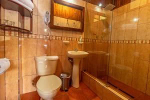 a bathroom with a toilet and a sink and a shower at El Jardín Hotel & Restaurante in Puyo