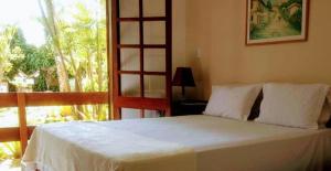 a bedroom with a white bed with a large window at Pousada Guaratiba in Prado