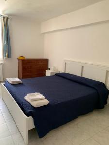 a bedroom with a blue bed with two towels on it at Viniola Apartment in Quartu SantʼElena