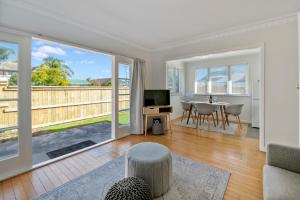 a living room with a television and a table with a chair at Bach on Pitau - Mt Maunganui Holiday Home in Mount Maunganui