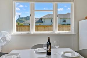 einen Tisch mit einer Flasche Wein und zwei Gläsern in der Unterkunft Bach on Pitau - Mt Maunganui Holiday Home in Mount Maunganui