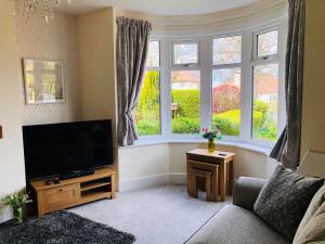 a living room with a flat screen tv and windows at Acacia Breezes - Delightful Scarborough Semi in Scarborough +17 photos