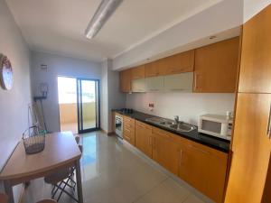 a kitchen with wooden cabinets and a sink and a table at Casa da Praia 901 in Portimão