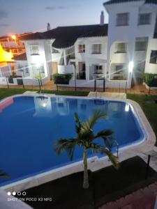 a large blue swimming pool in front of a house at Apartamento vacacional máximo 4 personas in Novo Sancti Petri