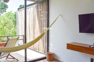 a hammock in a room with a window and a tv at Amaka Calma Tulum in Tulum