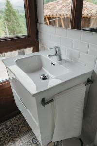 lavabo blanco en un baño con ventana en EL CORRAL DEL CARTERU - Casa Rosales, en Infiesto