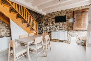 uma sala de jantar com mesa e cadeiras e uma parede de pedra em EL CORRAL DEL CARTERU - Casa Rosales em Infiesto