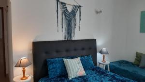 a bedroom with a bed with blue sheets and two lamps at Sagres Sunny Room with private bathroom 300m from the beach in Sagres