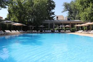 una gran piscina con sillas y sombrillas en Radisson Blu Hotel, Tashkent, en Tashkent