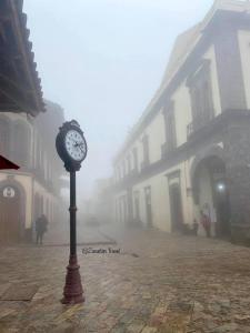a clock on a pole on a street in the fog at HOTEL CASA SILVESTRE in Zacatlán