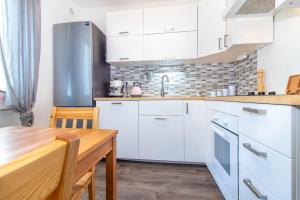 a kitchen with white cabinets and a wooden table at Apartmán Staré Hamry in Staré Hamry