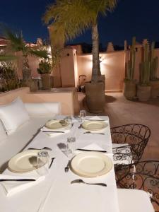 a table with white plates and silverware on a patio at Riad Les Nuits de Marrakech in Marrakesh