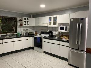 a kitchen with white cabinets and a stainless steel refrigerator at Sunrise by A-1 in Alajuela City