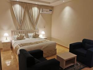 a bedroom with a large bed and two chairs at المبيت للشقق الفندقية in Sirr Āl Ghalīz̧