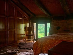 a bedroom with a bed and a window with a chair at La Cabaña del Beyu Pen in Amieva +8 photos