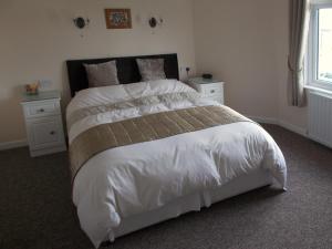 a bedroom with a large bed with white sheets and pillows at Penarth Guest House in Par