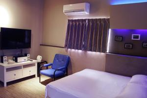 a hotel room with a bed and a chair and a television at Lazy House in Hengchun South Gate