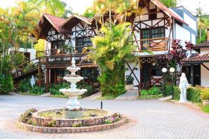 a fountain in front of a house with a building at Hotel Britannia in Penedo