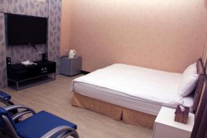 a bedroom with a bed and a flat screen tv at Lazy House in Hengchun