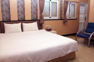 a bedroom with a large white bed and a blue chair at Lazy House in Hengchun