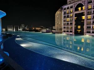 a swimming pool at night with buildings at FREE NETFLIX! ZAs Suite at Troika Residence, KB in Kota Bharu