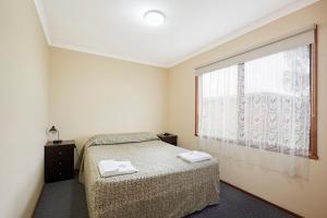 a bedroom with a bed and a large window at Allestree Holiday Units in Portland