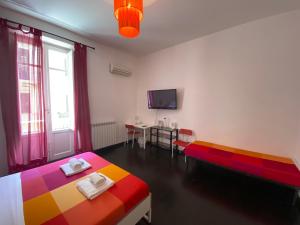 a room with two beds and a table and a tv at Liolà Home Palermo in Palermo