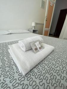 a bed with towels and a book on it at Liolà Home Palermo in Palermo