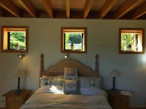a bedroom with a bed and two windows at Stunning Scandi Style Home Overlooking Lake Wanaka in Wanaka