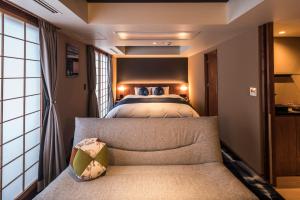 Homm Stay Nagi Arashiyama Kyoto By Banyan Group في كيوتو: غرفة نوم بسرير واريكة في غرفة