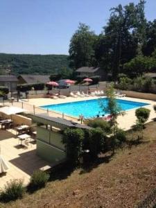 una gran piscina con sillas y sombrillas en Chalet les Hameaux du Perrier, en Lissac-sur-Couze