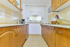 a kitchen with wooden cabinets and a window at Apartament u Ani 1 in Dźwirzyno
