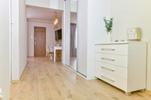 a kitchen with a white dresser and a dining room at Apartament u Ani 2 in Dźwirzyno