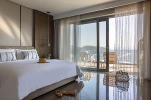 a bedroom with a large bed and a balcony at METT Hotel & Beach Resort Bodrum in Bodrum City