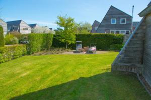 een achtertuin met een gazon en een huis bij Fries Vakantiehuis, grote tuin, nabij het Pikmeer in Grou