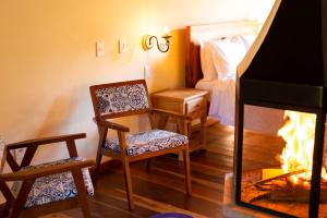 een woonkamer met een open haard, stoelen en een bed bij Pousada Chalé Amoreira in Visconde De Maua