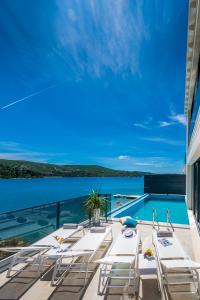 une terrasse avec des chaises blanches et une piscine dans l'établissement Villa Sol del Mar III, à Slano