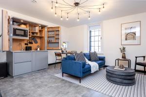 a living room with a blue couch and a kitchen at The Brewers Rooms Contemporary Aparthotel in Edinburgh