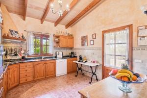 a kitchen with wooden cabinets and a bowl of fruit on a table at Finca Es Pujolet in Alcudia