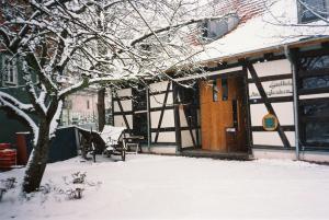 un edificio cubierto de nieve con un banco y un árbol en Gasthof-Gästehaus am Storchenturm, en Eisenach