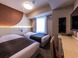 um quarto de hotel com duas camas e uma televisão de ecrã plano em APA Hotel Shin Osaka-Eki Tower em Osaka