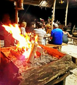 a group of people sitting around a large grill with flames at Alter Native Stay in Tapokreng +63 photos