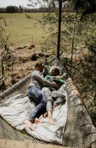 - un homme et une femme dormant sur un hamac dans l'établissement Palapinė medyje, à Barkellai
