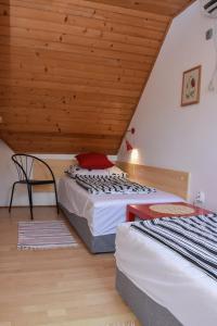 two beds in a room with a wooden ceiling at Lenart House 2 in Siófok
