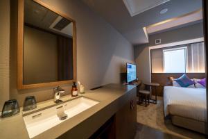 a bathroom with a sink and a bed and a mirror at Hotel Oriental Express Fukuoka Nakasu Kawabata in Fukuoka