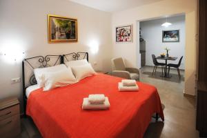 a bedroom with a red bed with two towels on it at Nika Family Apartments in Dubrovnik