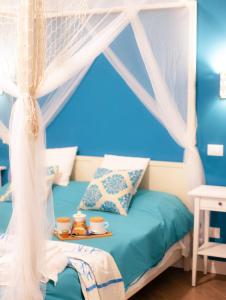 B&B Carella في باليرمو: غرفة نوم مع سرير مظلة مع كوبين على صينية